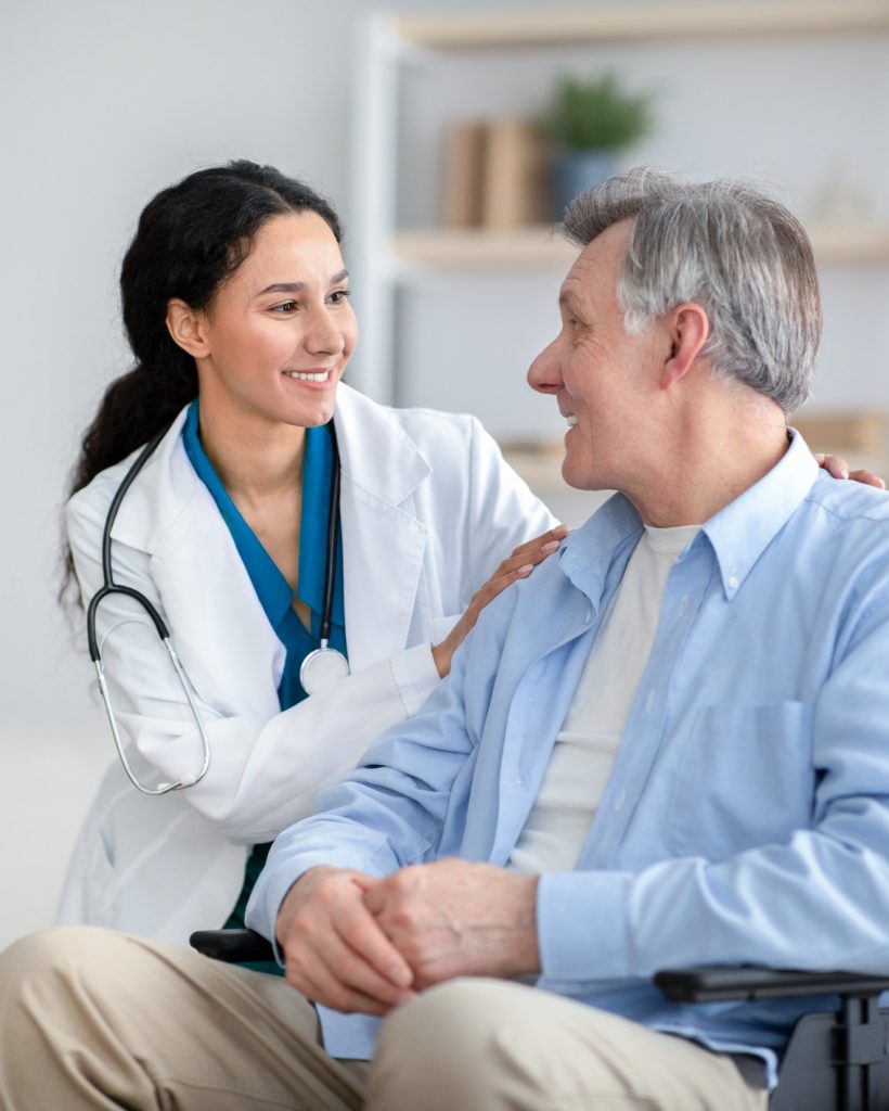 impaired-senior-man-in-wheelchair-and-young-nurse-taking-care-of-him-at-home